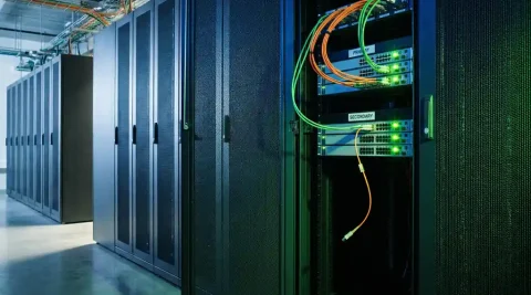 Serverrack in datacenter met loshanggende glasvezelkabel en groene statusindicatoren op redundante netwerkswitches.